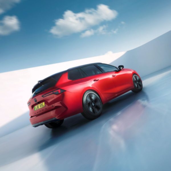 Red sports car driving on a reflective surface, viewed from behind.