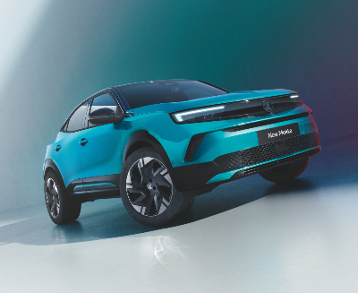Turquoise car with modern design and black grille, viewed from a low angle.