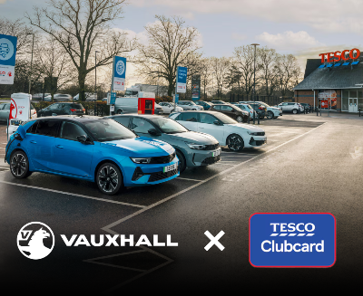 Electric cars charging at a Tesco with Vauxhall and Tesco Clubcard logos visible.
